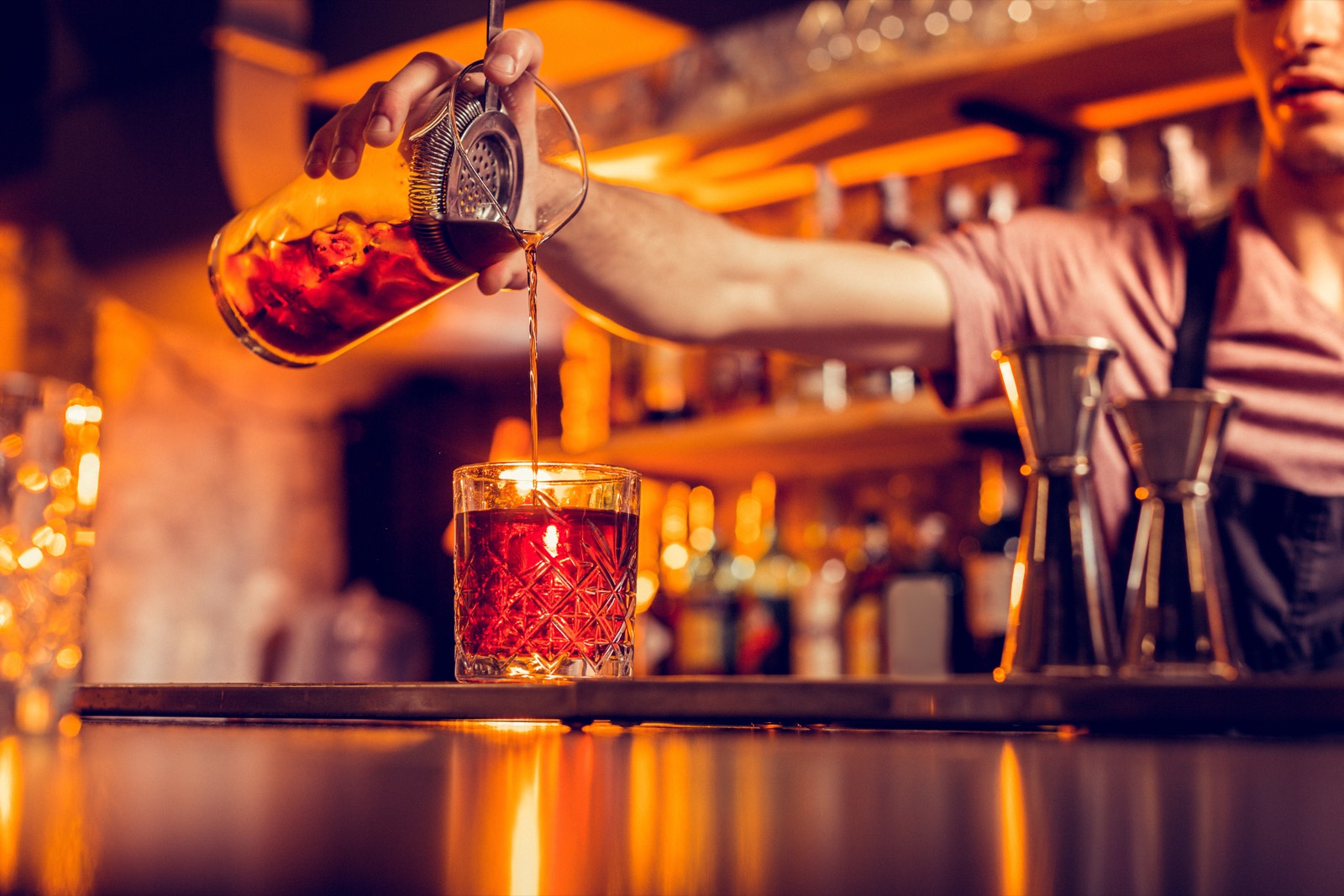 A bartender pouring a cocktail at night