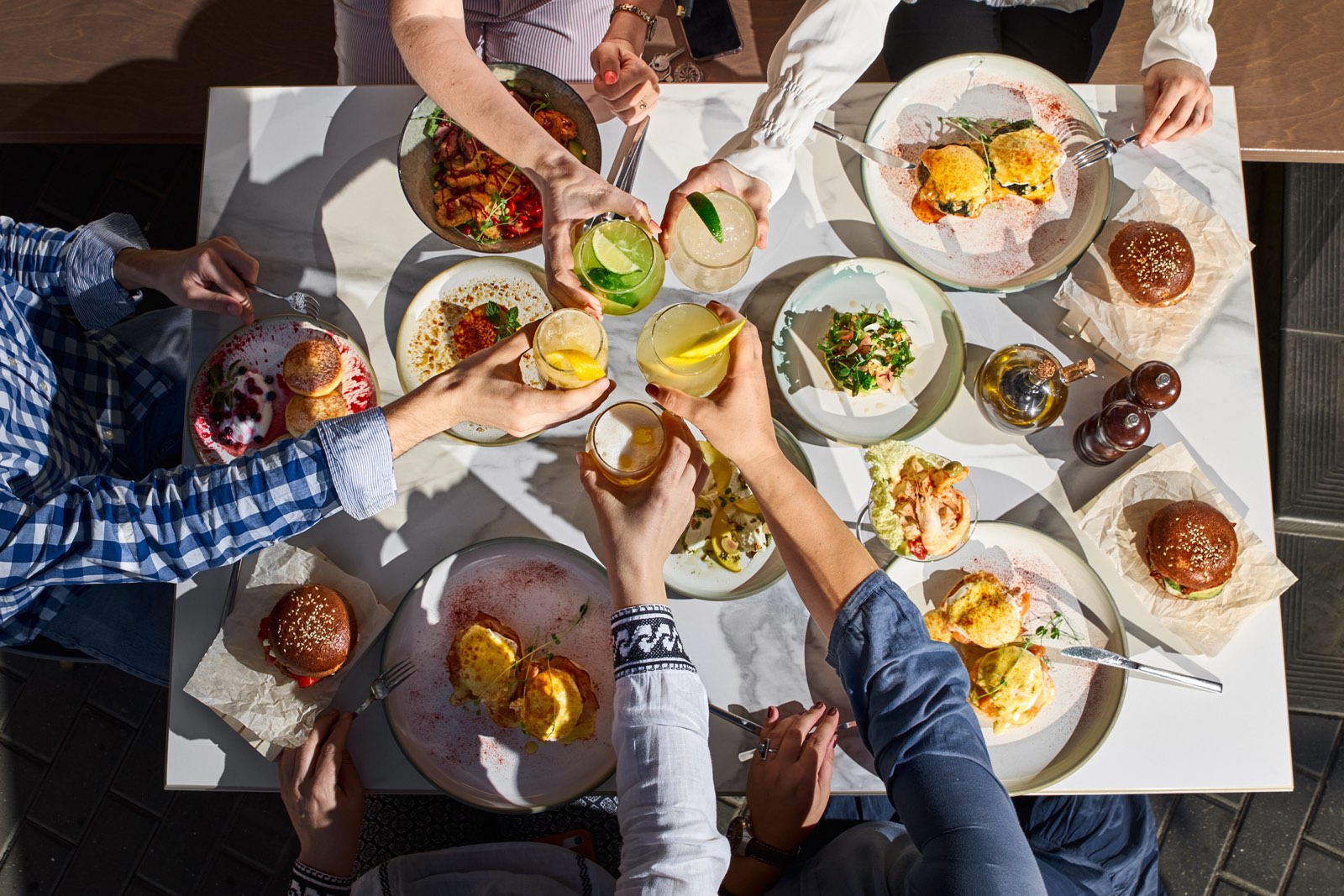 Friends toasting drinks over a table of shared dishes