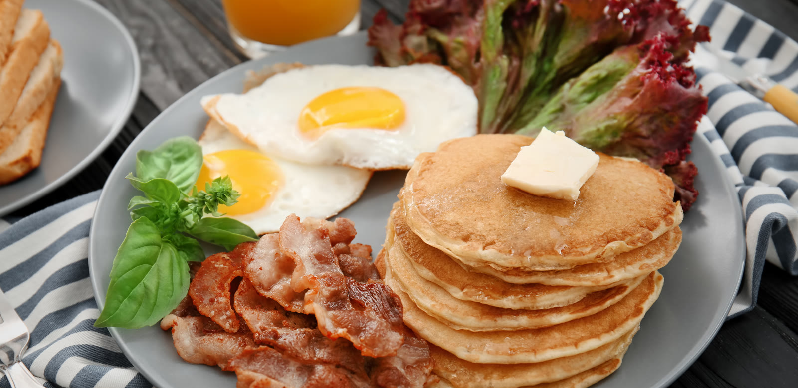 A breakfast plate of pancakes, fried eggs and bacon