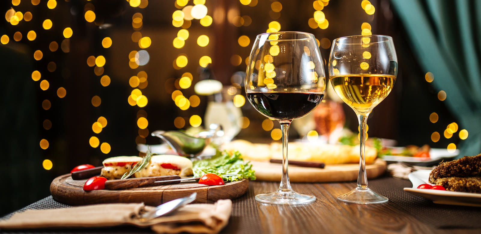 Red and white wine with dinner under warm string lights