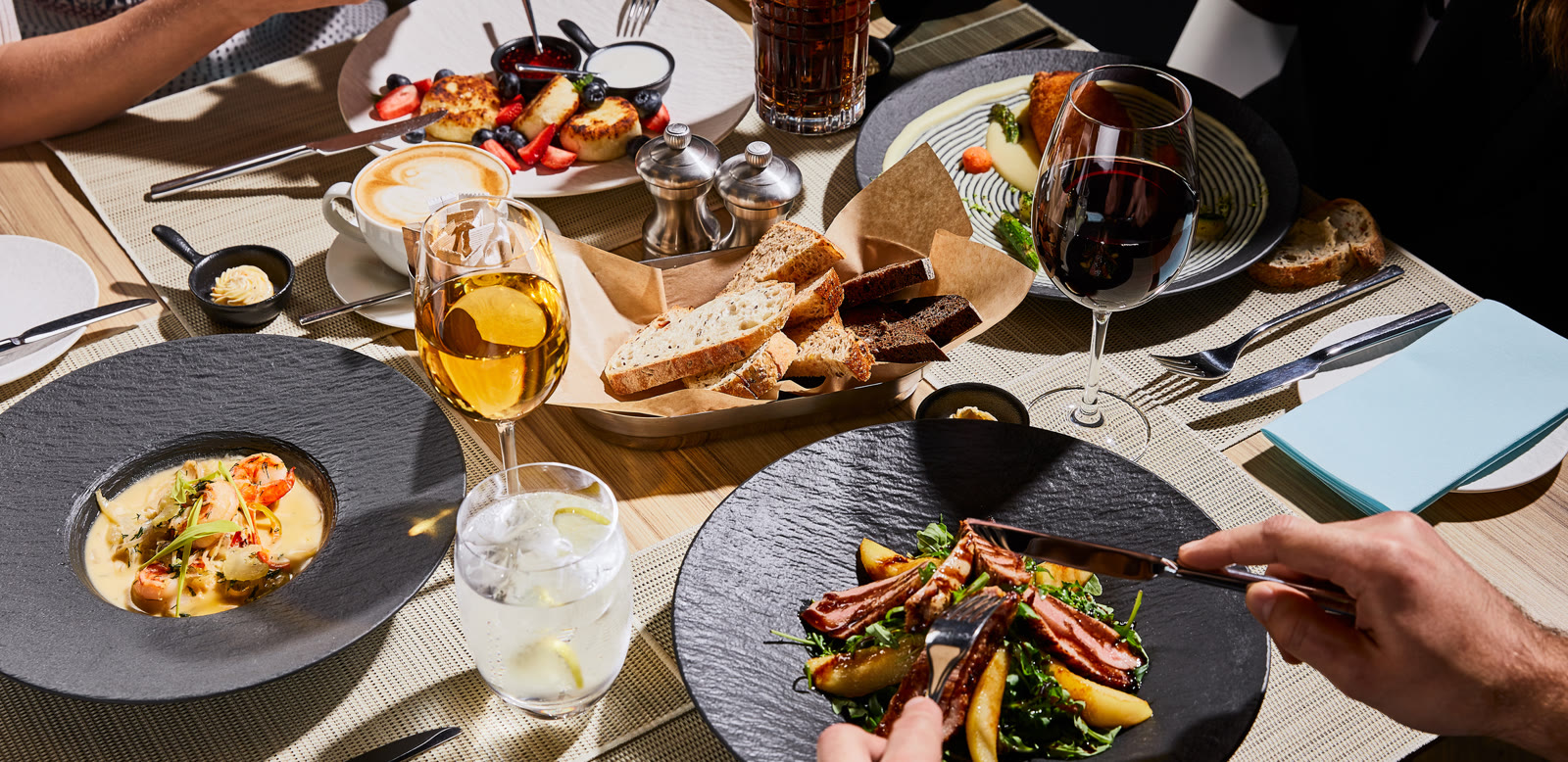 A restaurant table set with plates, bread and glasses of wine