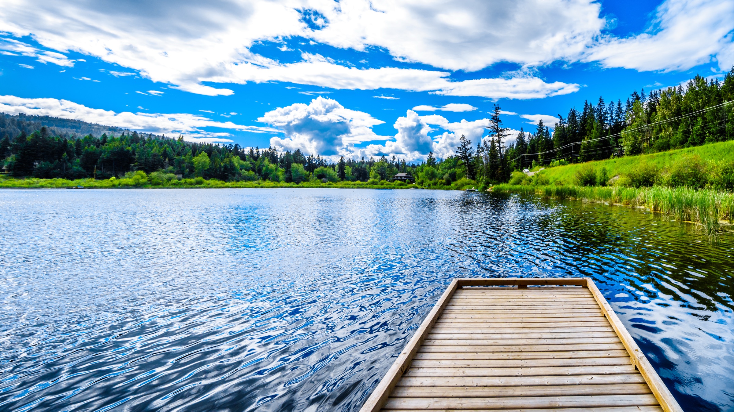 Un quai de pêche en bois sur un lac calme bordé de forêt en C.-B.