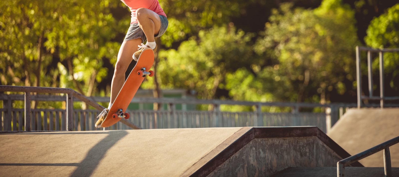 A skateboarder riding a ramp at a tree-lined skate park
