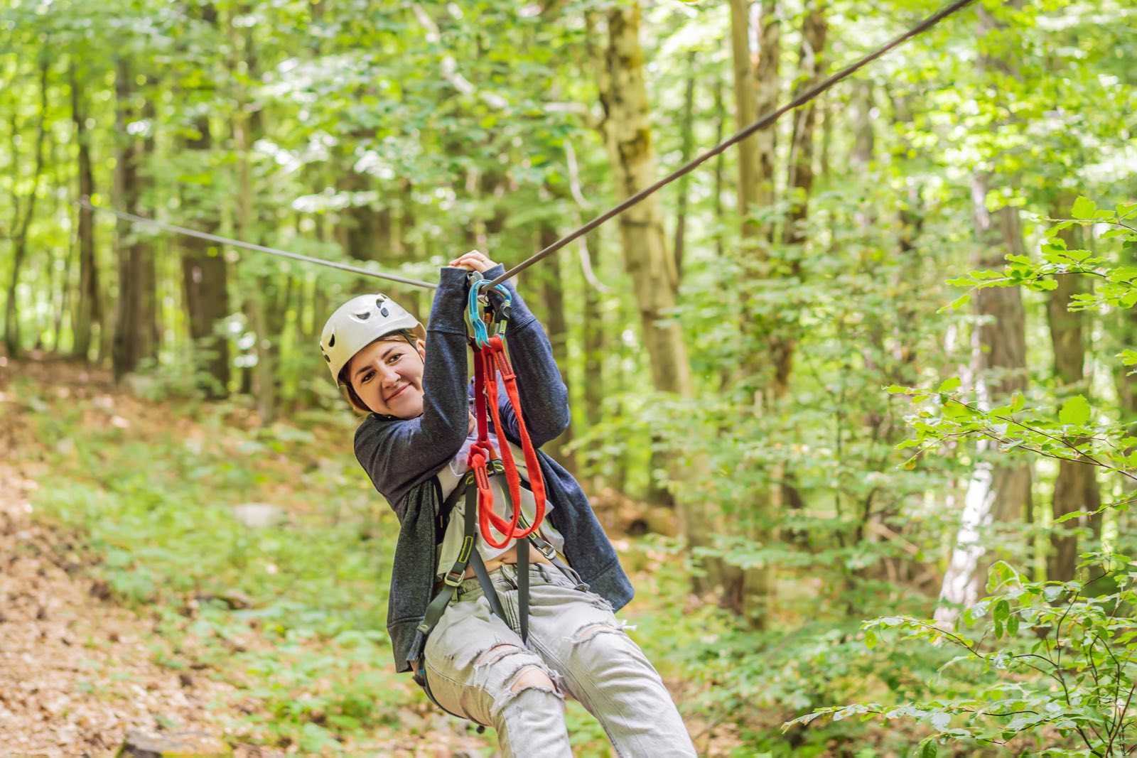 A woman flying along a zipline through the forest