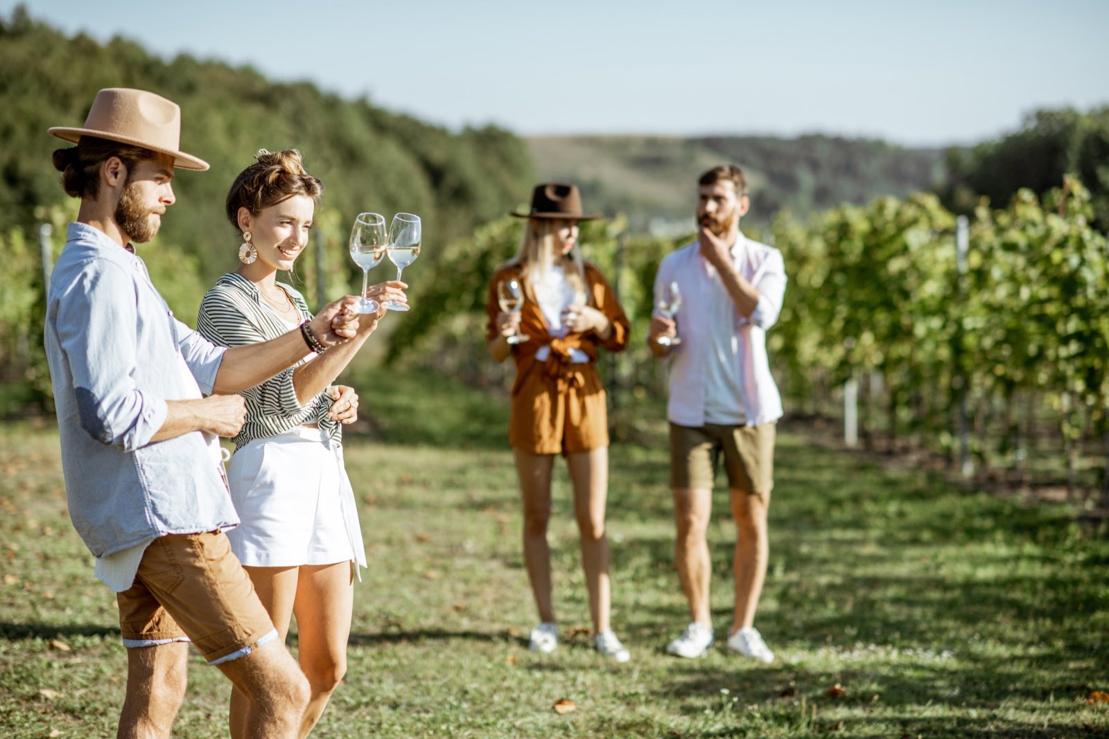 Friends tasting wine in a vineyard on a sunny morning