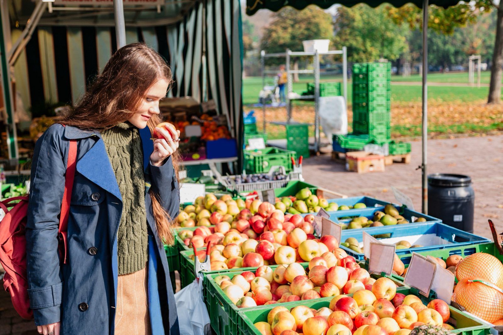 A woman smelling an apple at a farmers market stall